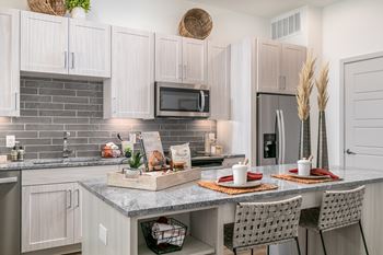 A kitchen with a table set for two with plates and glasses.